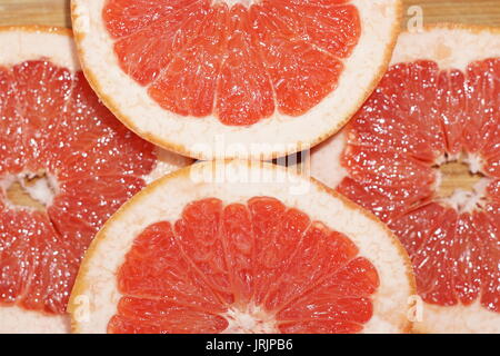 Grapefruit in Scheiben schneiden und auf Holzplatte scheint von reflektierten Lichts angeordnet Stockfoto