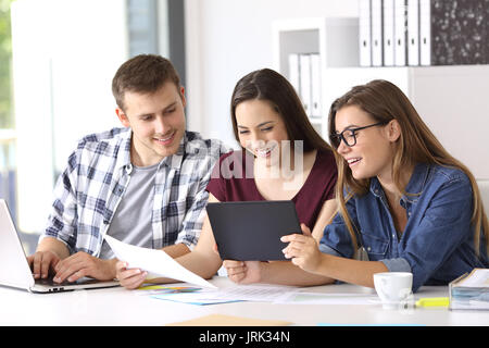 Drei glückliche Mitarbeiter arbeiten auf der Linie mit einer Tablette und Dokumente im Büro Stockfoto