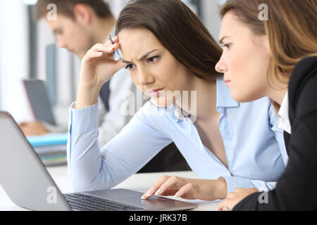 Zwei besorgt, Geschäftsfrauen, die in Linie mit einem Laptop im Büro Stockfoto