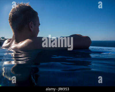 Ein muskulöser Teenager genießt die Aussicht in einen Infinity-pool Stockfoto