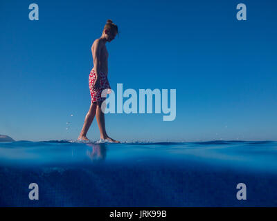 Ein gelangweilter teenaged Jungen Spaziergänge am Rande einer Infinity Pool im Urlaub Stockfoto