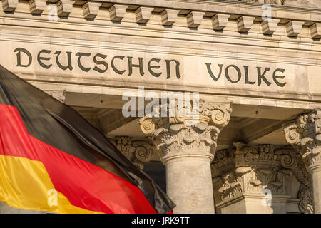 Berliner Reichstag Vorderseite, Detail der Inschrift an der Fassade der Deutschen Parlament Gebäude (der Bundestag) in Berlin mit Fahne im Vordergrund. Stockfoto