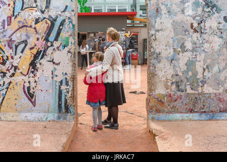 Mutter und Tochter, Rückansicht einer Mutter und Tochter, die zwischen zwei Mauerabschnitten im Mauermuseum in Berlin stehen Stockfoto