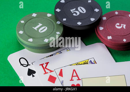 Karten Poker Deck Englisch, Pik Dame, Rot König von Diamanten und Herz Ass neben Tabs von 10, 50 und 5 auf grünem Hintergrund Stockfoto