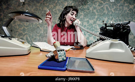 Junge Sekretärin eine Zigarette, während Sie telefonieren, 60er Szene Stockfoto