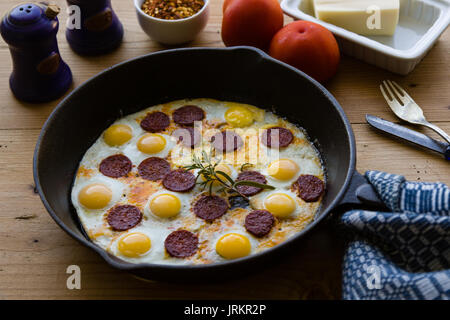 Gebratene Wachtel Eier mit Wurst in Schwarz pan Stockfoto