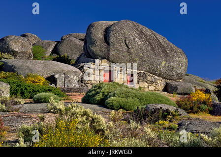 Kleines Haus aus Stein unter riesigen Granitfelsen Stockfoto