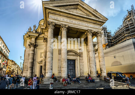 Die Basilika von Santa Maria del Popolo in der Piazza del Popolo in Rom Italien an einem heißen, sonnigen Tag, wie Einheimische und Touristen in den Schatten auf den Stufen sitzen Stockfoto