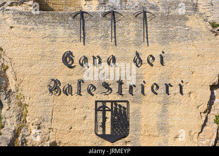 Eine Wand mit Wappen und einige Armbrüste in der Cava dei Balestrieri in San Marino Stockfoto