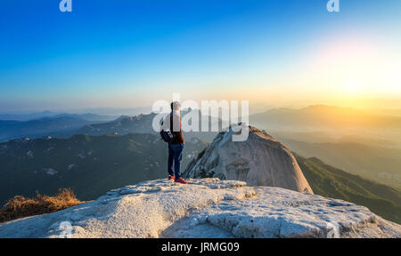 Man steht auf dem Gipfel der Stein in Bukhansan Nationalpark, Seoul in Südkorea und beobachten den Sonnenaufgang. Schöner Moment, das Wunder der Natur. Stockfoto