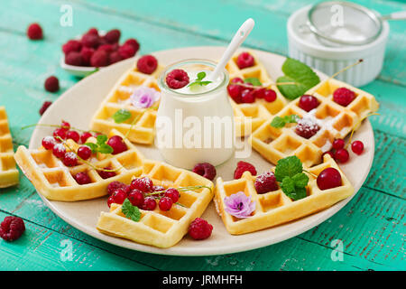 Belgische Waffeln mit Himbeeren und Joghurt an der Platte. Stockfoto