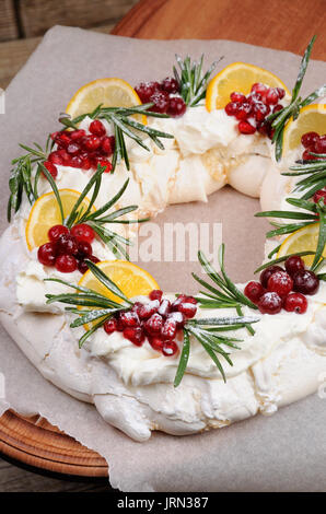 Pavlova Kuchen in der Form von ein Adventkranz der Meringue mit Rahm, Granatapfel, Cranberry, Rosmarin-Zweige Stockfoto