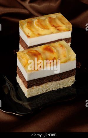 Kuchen aus Karamell, Apfel Mousse, Schokolade und Mandeln Biskuit mit einer Schicht Gelee karamellisiertem Apfel Scheiben gestapelt Stockfoto