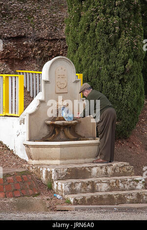 Alter Mann eine Flasche Trinkwasser in einem Brunnen, Spanien Stockfoto