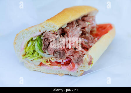 Schinken und Salat submarine Sandwich von frisch geschnittenem Baguette auf rustikalen Holzmöbeln Brot. Stockfoto