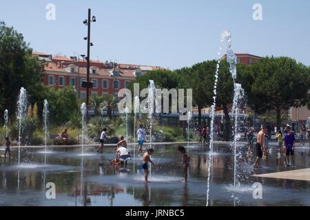 Touristenfamilien planschen in Wasserfontänen am Massena-Platz, Nizza, Frankreich Stockfoto