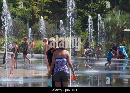 Touristenfamilien planschen in Wasserfontänen am Massena-Platz, Nizza, Frankreich Stockfoto