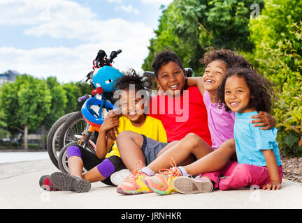 Portrait der afrikanischen Kinder umarmen und sitzt neben ihr Fahrrad auf Radweg an einem sonnigen Tag Stockfoto