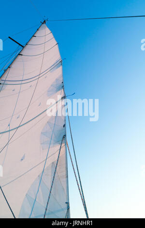 Teil gehisst Großsegel von Segelboot mit Leech, Rigging und Reffleinen gegen den blauen Himmel Stockfoto