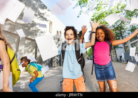Gerne sehr verlassen junge werfen Papiere in der Luft mit Freunden in der Nähe der Schule Tür Stockfoto