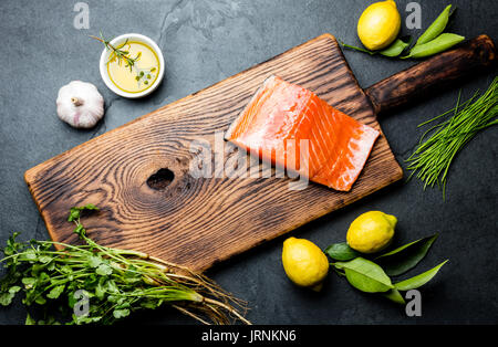 Rohem Lachsfilet, Spargel, Zitronen und Kräutern auf Holzbrett. Speisen kochen Hintergrund mit Textfreiraum. Ansicht von oben Stockfoto
