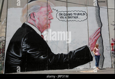 Bethlehem, Westjordanland, Palästinensische Gebiete. 6. August 2017. Ein Tourist Stand vor der ein Graffiti Darstellung von US-Präsident Donald Trump auf umstrittenen israelischen Sperranlage im Westjordanland Stadt von Bethlehem am 8. August 2017 Credit: Shadi Hatem/APA Bilder/ZUMA Draht/Alamy Live News Stockfoto