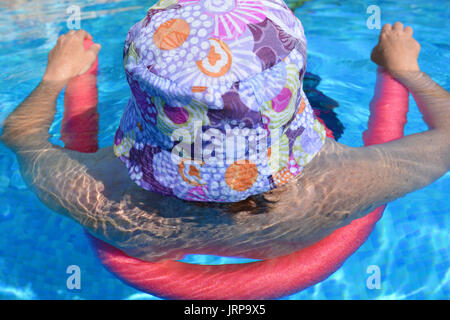 Sommer Vibes! Frau floating in einem Schwimmbad mit einem Pool Nudel. Stockfoto