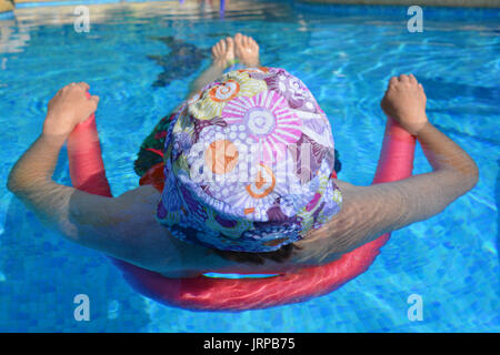 Sommer Vibes! Frau floating in einem Schwimmbad mit einem Pool Nudel. Stockfoto