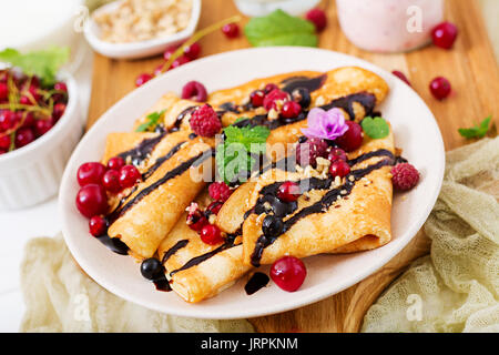 Pfannkuchen mit Schokolade, Honig, Nüsse und Beeren. Leckeres Frühstück. Stockfoto