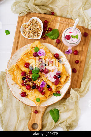 Pfannkuchen mit Joghurt, Honig, Nüsse und Beeren. Leckeres Frühstück. Flach. Ansicht von oben Stockfoto