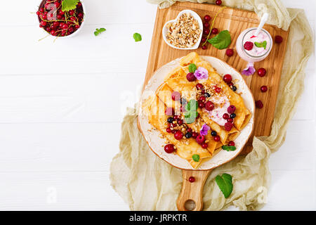 Pfannkuchen mit Joghurt, Honig, Nüsse und Beeren. Leckeres Frühstück. Flach. Ansicht von oben Stockfoto