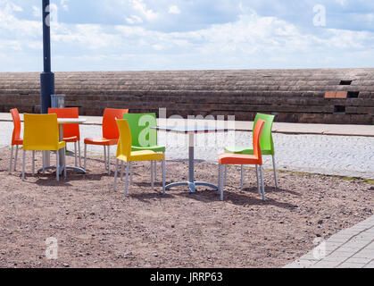 Leere Tabellen und schönen bunten Plastikstühle in einem Straßencafe in Europa. Stockfoto