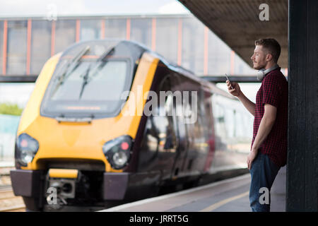Mann am Bahnhof mit Handy auf Plattform Stockfoto