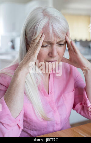 Reife Frau zu Hause leiden unter Kopfschmerzen. Stockfoto