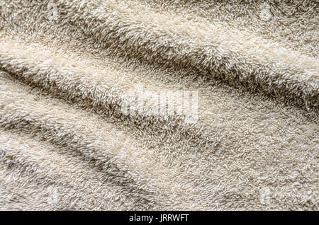 Beiläufig liegende Handtuch der beigen Farbe. Falten an der Oberfläche eines beige towelbackground Stockfoto