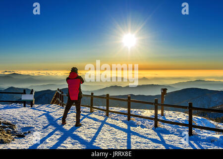 Bergsteiger steht auf dem Höhepunkt im Winter, Deogyusan Nationalpark in Südkorea und beobachten den Sonnenaufgang. Schöner Moment, das Wunder der Natur. Stockfoto