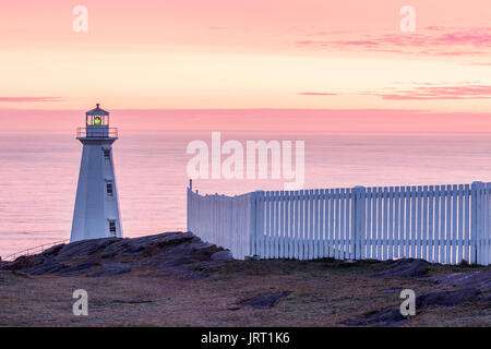 Die 1955 konkrete Leuchtturm und einem weißen Lattenzaun am Cape Spear National Historic Site von Kanada bei Sonnenaufgang. Cape Spear, St. John's, Neufundland. Stockfoto