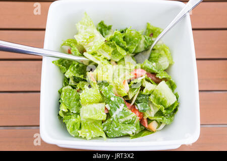 Gesundes Essen, Caesar Salat in einer weißen Schüssel mit Gabel und Löffel auf hölzernen Tisch, gut für die Gesundheit Artikel Stockfoto