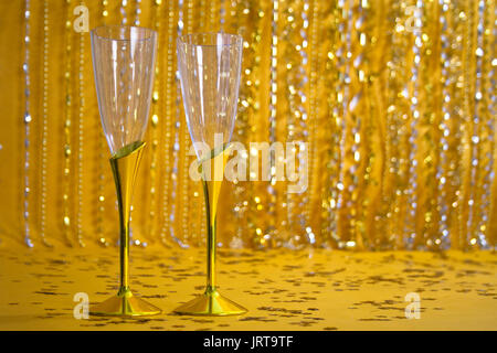 Zwei Champagnergläser sitzen auf einem goldenen Boden bscked durch einen funkelnden, Gold und Silber. Stockfoto