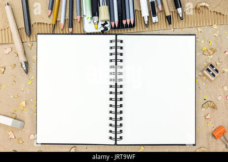 Leere Skizzenbuch und Stifte zum Zeichnen auf Braun künstlerischer Hintergrund der Ansicht von oben Stockfoto