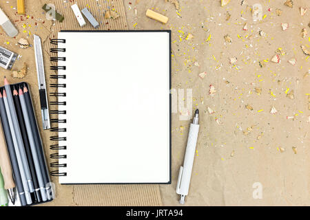Satz von verschiedenen Bleistifte und bunte Kreiden mit offenen leere Notepad auf Schreibtisch Stockfoto