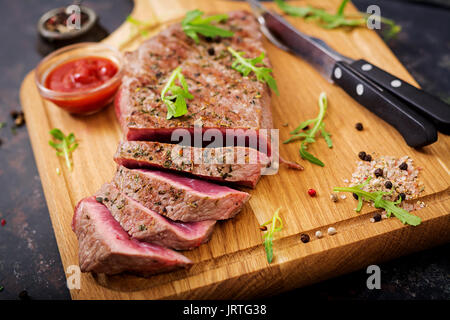 Saftiges steak selten Rindfleisch mit Gewürzen auf einem Holzbrett Stockfoto