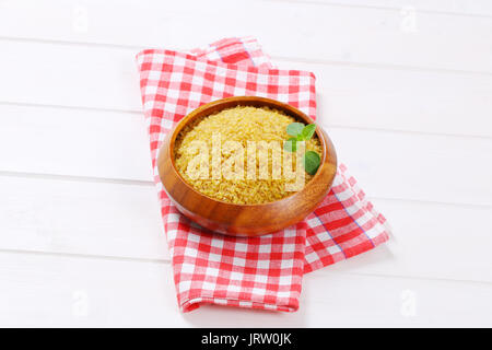 Schüssel mit trockenen Weizen Bulgur auf karierten Geschirrhandtuch Stockfoto
