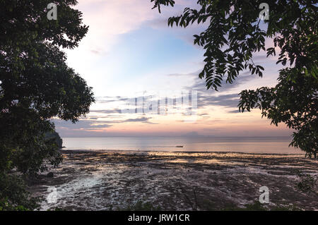 Bunte sunrise von Railay Beach mit einem traditionellen Long tail Boot im Meer. Stockfoto