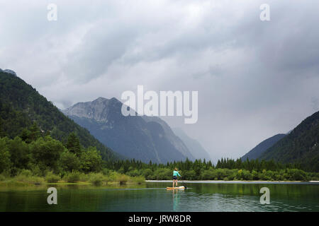 Frau in Shorts padlling auf alpinen See. Lago di Predil, Italien. Stockfoto