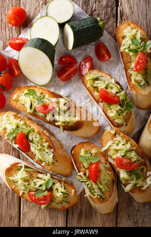 Bruschetta mit geriebenen Zucchini und Tomaten close-up und Zutaten auf den Tisch. Vertikale Ansicht von oben Stockfoto