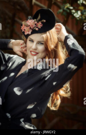 Lächelnde junge Frau mit Blumen vintage kleid und hut Stockfoto