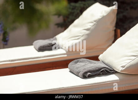 Hotel Rest, Ferien und Sommer Freude Konzept: Detailansicht schöne Liegestühle mit Auflagen und Handtücher für Entspannung, Unterhaltung, solar Spa Resort in der Nähe von Pool, Liegestühle aus Holz und Leder. Stockfoto