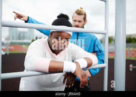 Portrait von Müde chubby Frau lehnte sich auf Pull-up Bar Stockfoto
