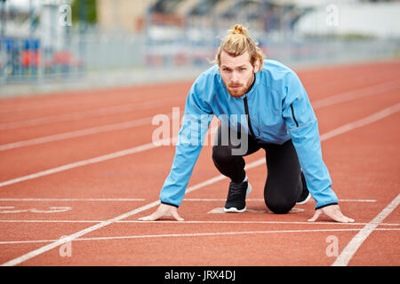 Entschlossene junge Athleten am Start bei Leichtathletik Stadion Stockfoto